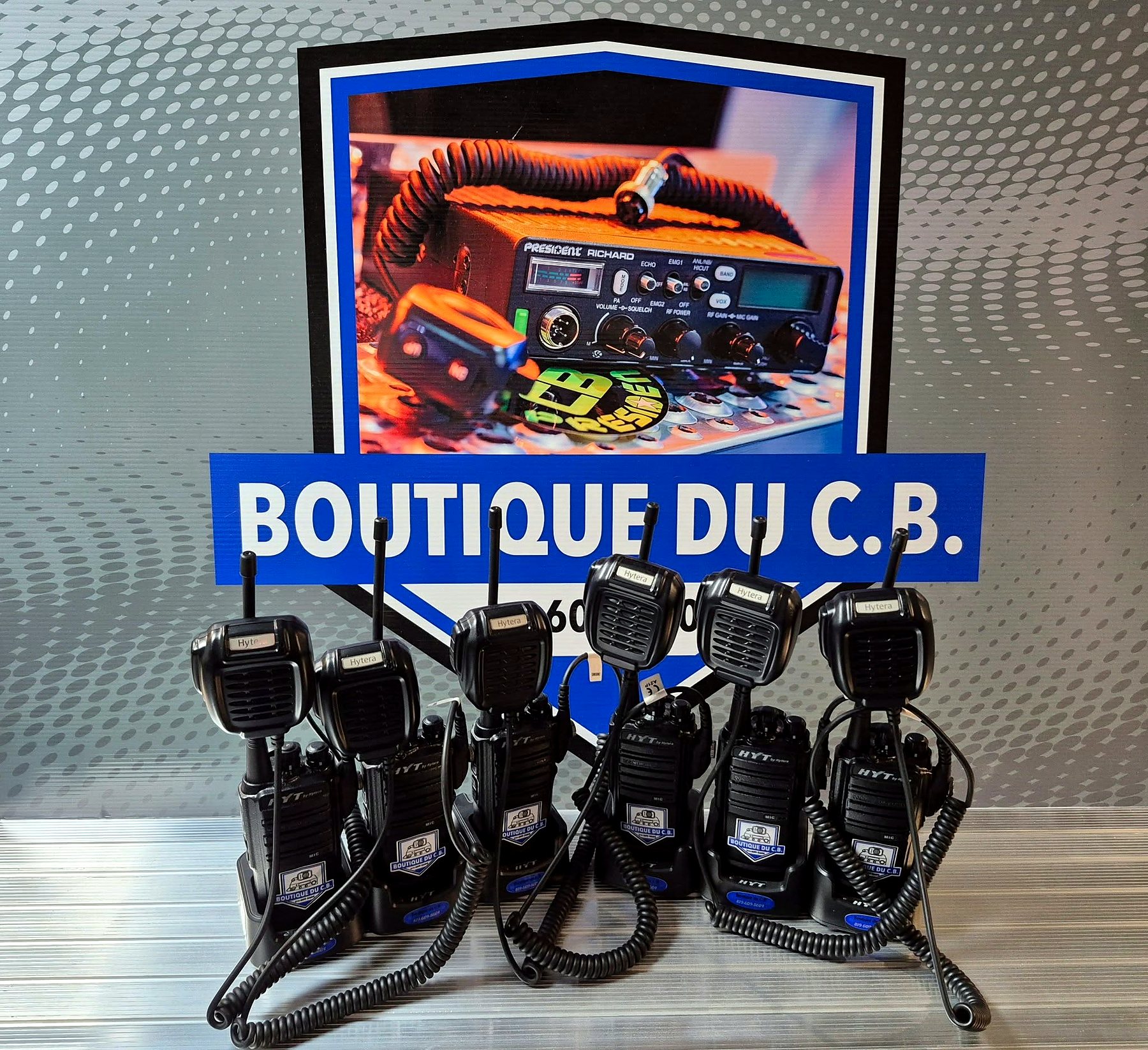 Radios portatives alignées sous l'écusson Boutique du C.B., prêtes à la location