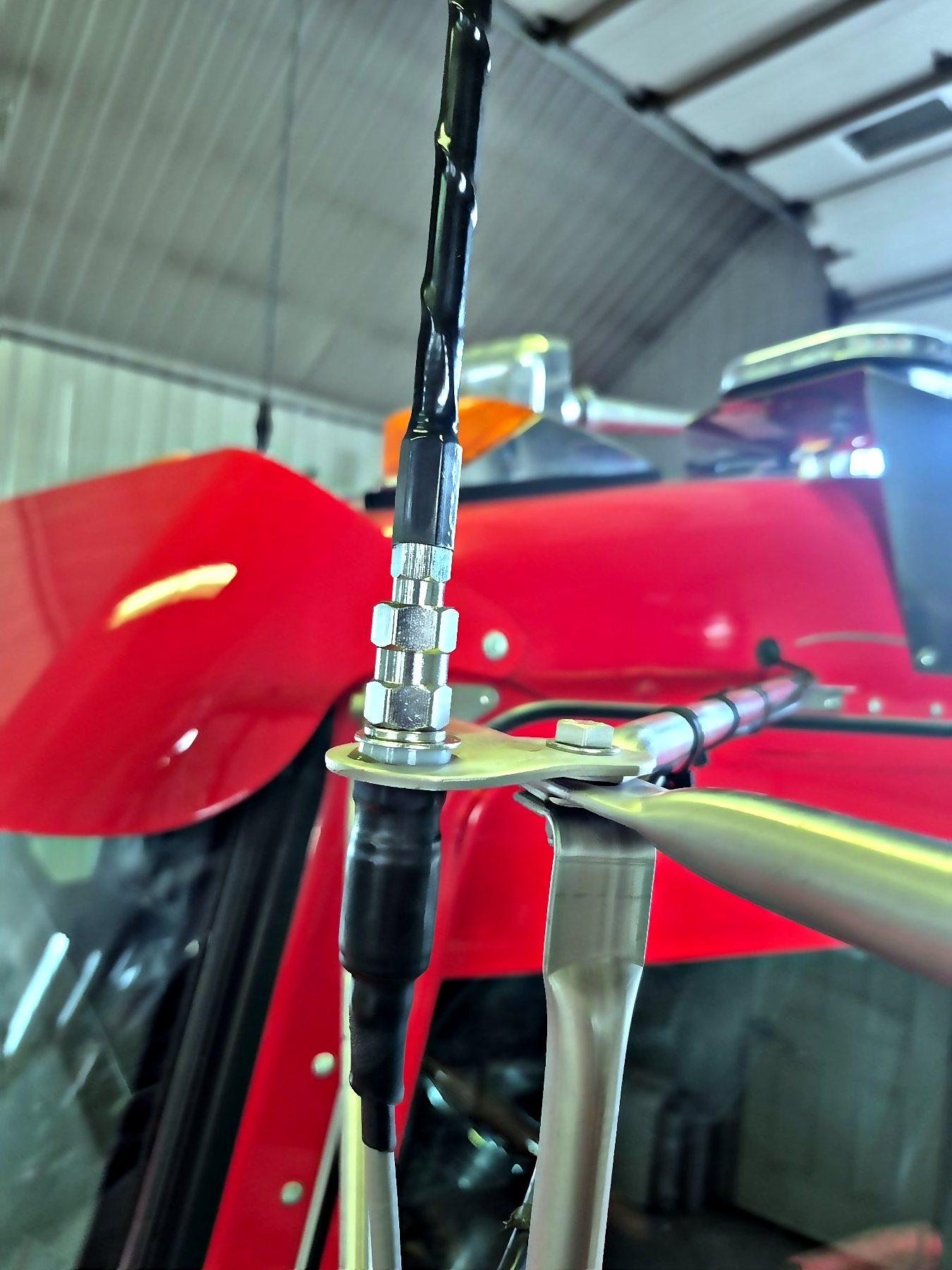 Antenne CB fixée sur un tracteur rouge, vue de près